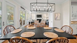 Un coin repas avec une table noire, des sets de table en fibres tressées et des chaises en bois.