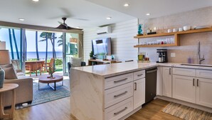 A modern kitchen with a large island, white cabinetry, and a flat-screen TV.