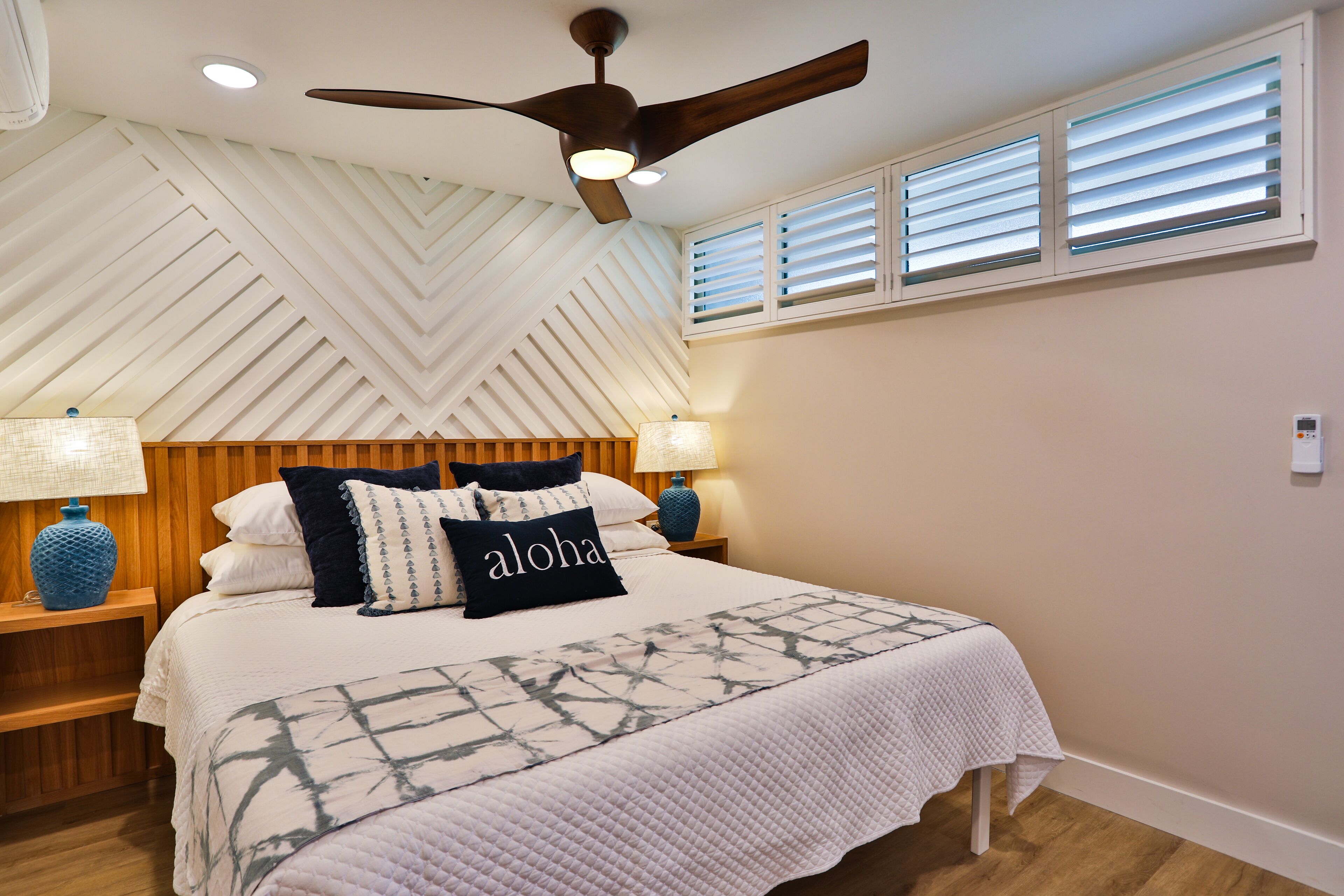 A bedroom with a bed, nightstands, a ceiling fan, and a window with blinds.