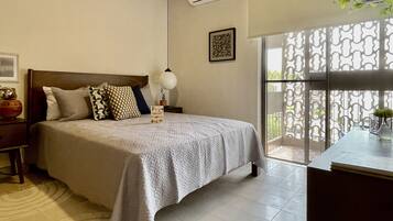 Un dormitorio con cama, mesita de noche, lámpara, aire acondicionado y vistas al exterior.