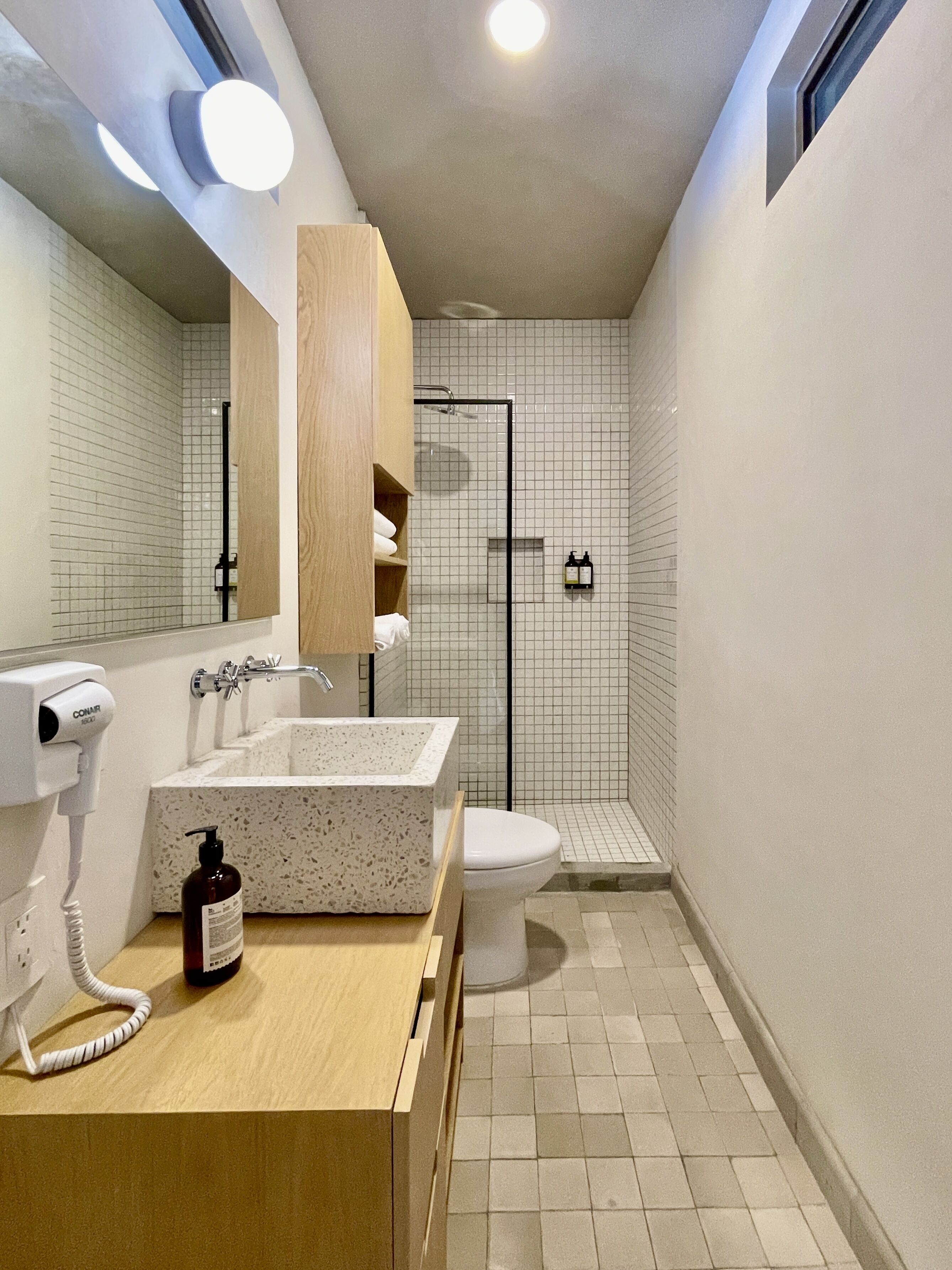 A modern bathroom with a freestanding sink, a toilet, and a shower enclosure.