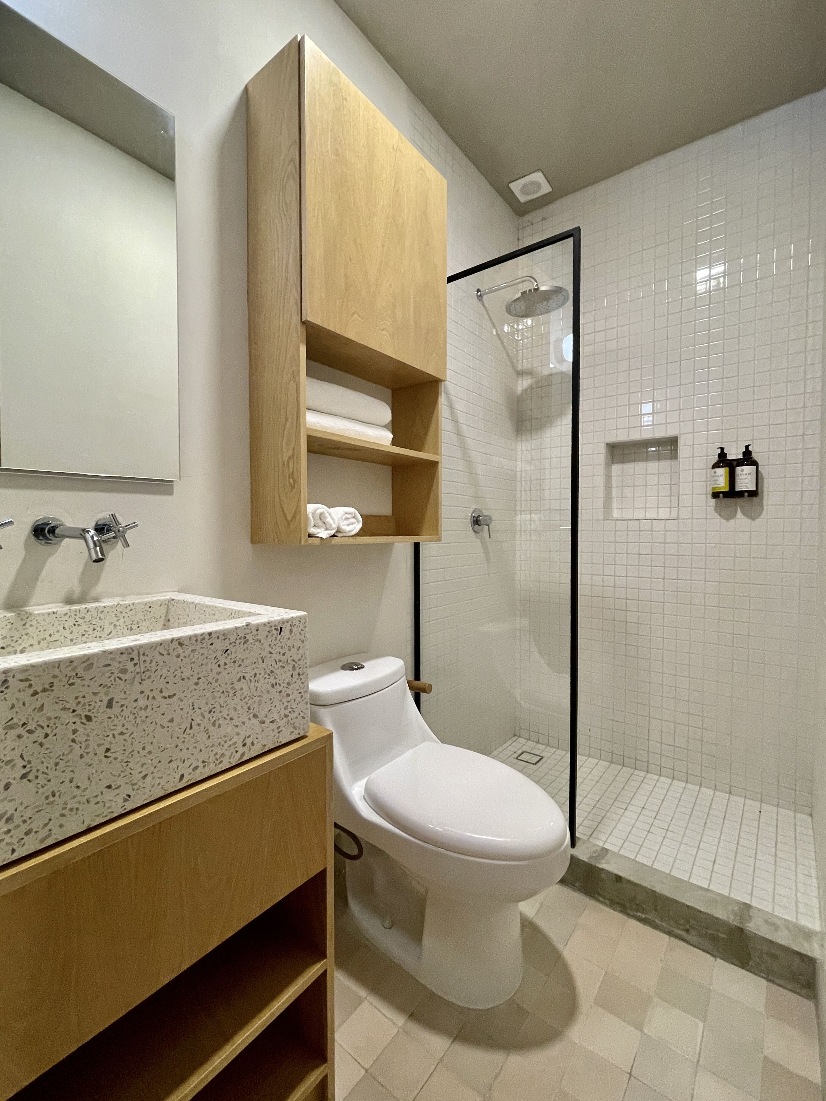 Ein modernes Badezimmer mit freistehender Toilette, einem Granitwaschbecken und einem Holzauszug.