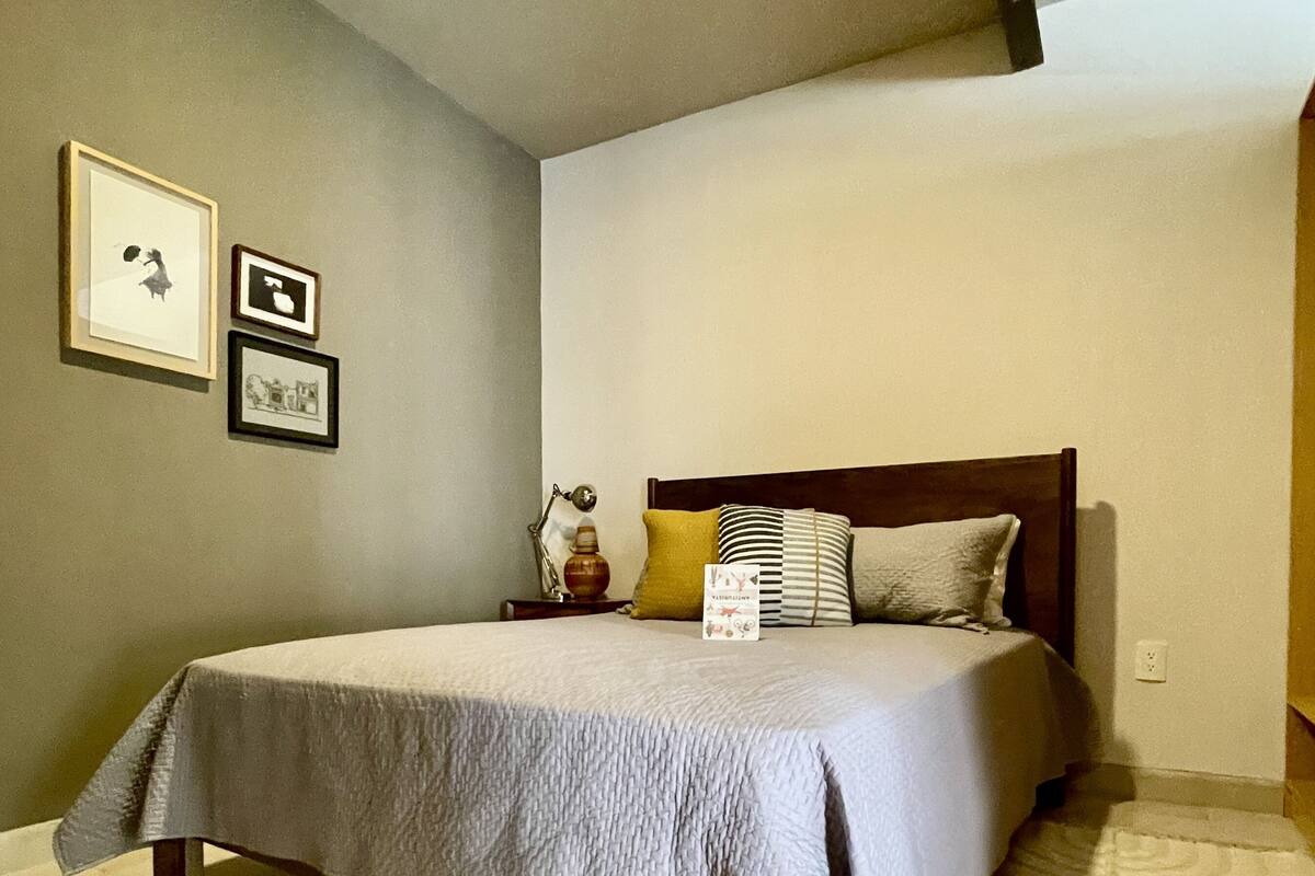 Een slaapkamer met een groot bed, een nachtkastje en drie ingelijste foto’s aan de muur.