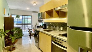 A modern kitchen with stainless steel appliances, wooden cabinets, and a large window providing natural light. - Casa San Fernando by Barrio México (Guadalajara)