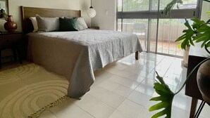 A bedroom with a bed, bedside table, lamp, and a large window. - Casa San Fernando by Barrio México (Guadalajara)