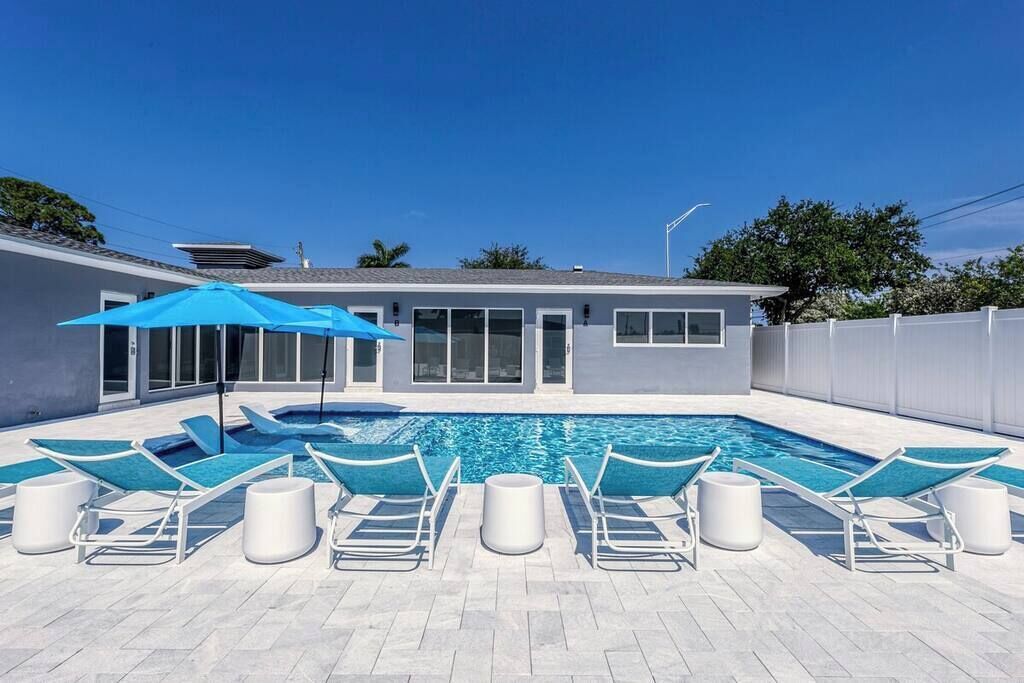 A swimming pool with lounge chairs and a blue umbrella.