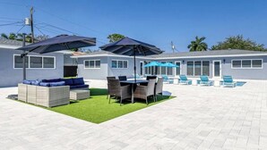 A patio area with outdoor furniture, a pool, and umbrellas. - 2025-C Sunshine Manors (Wilton Manors)