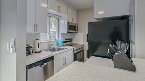 A modern kitchen with stainless steel appliances, white cabinetry, and a granite countertop.