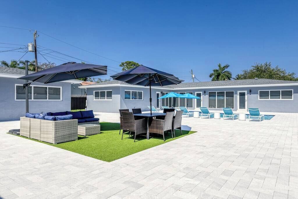A patio area with outdoor furniture, a pool, and umbrellas.