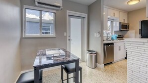 A compact kitchen with a marble countertop, stainless steel appliances, and a trash can.
