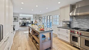A modern kitchen with a central island, stainless steel appliances, and a view to the backyard. - Hidden Oaks Farmhouse by Avantstay Hot Tub, Deck (Atascadero)