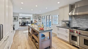 A modern kitchen with a central island, stainless steel appliances, and a view to the outside. - Hidden Oaks Farmhouse by Avantstay Hot Tub, Deck (Atascadero)