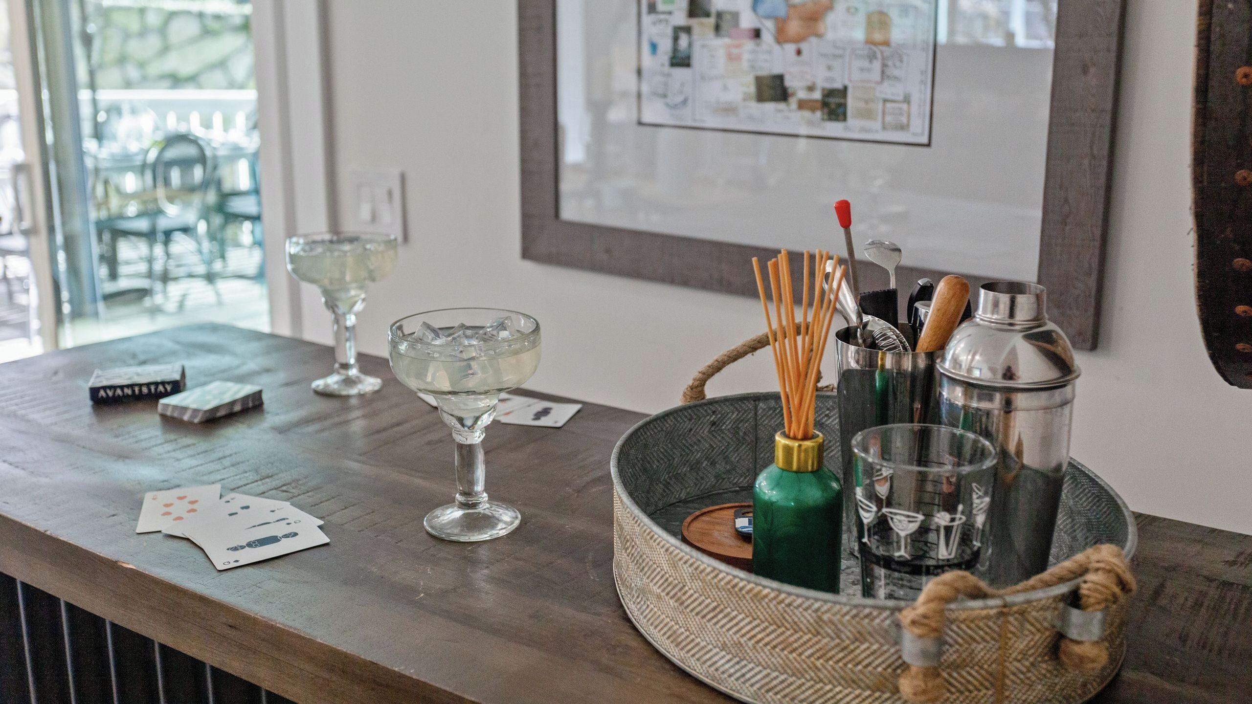 A bar area with a tray holding a cocktail shaker, a bottle, and a glass.