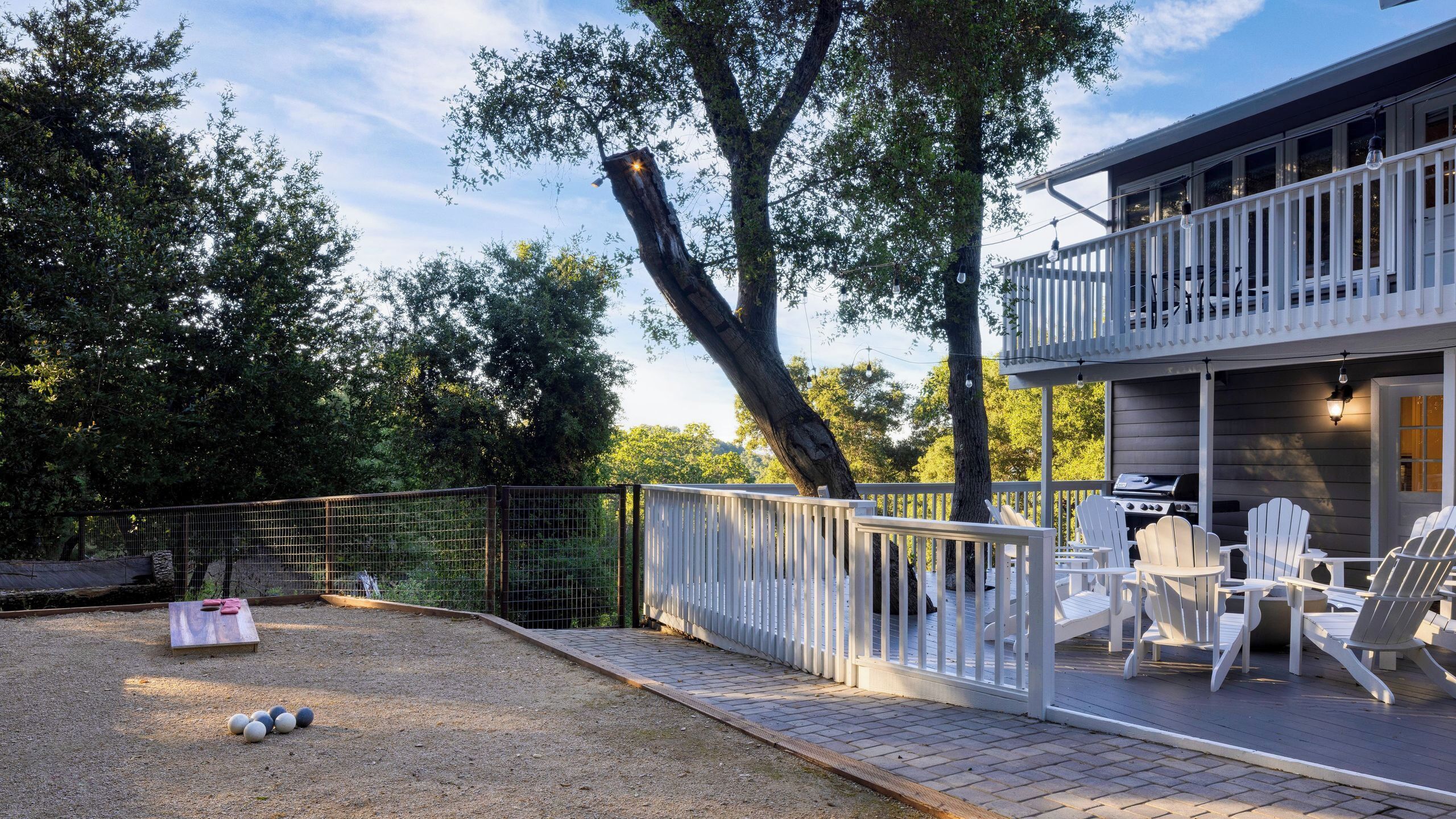 Eine Terrasse mit Sitzgelegenheiten im Freien, einem Grill und einem eingezäunten Bereich mit Tisch und Bällen.