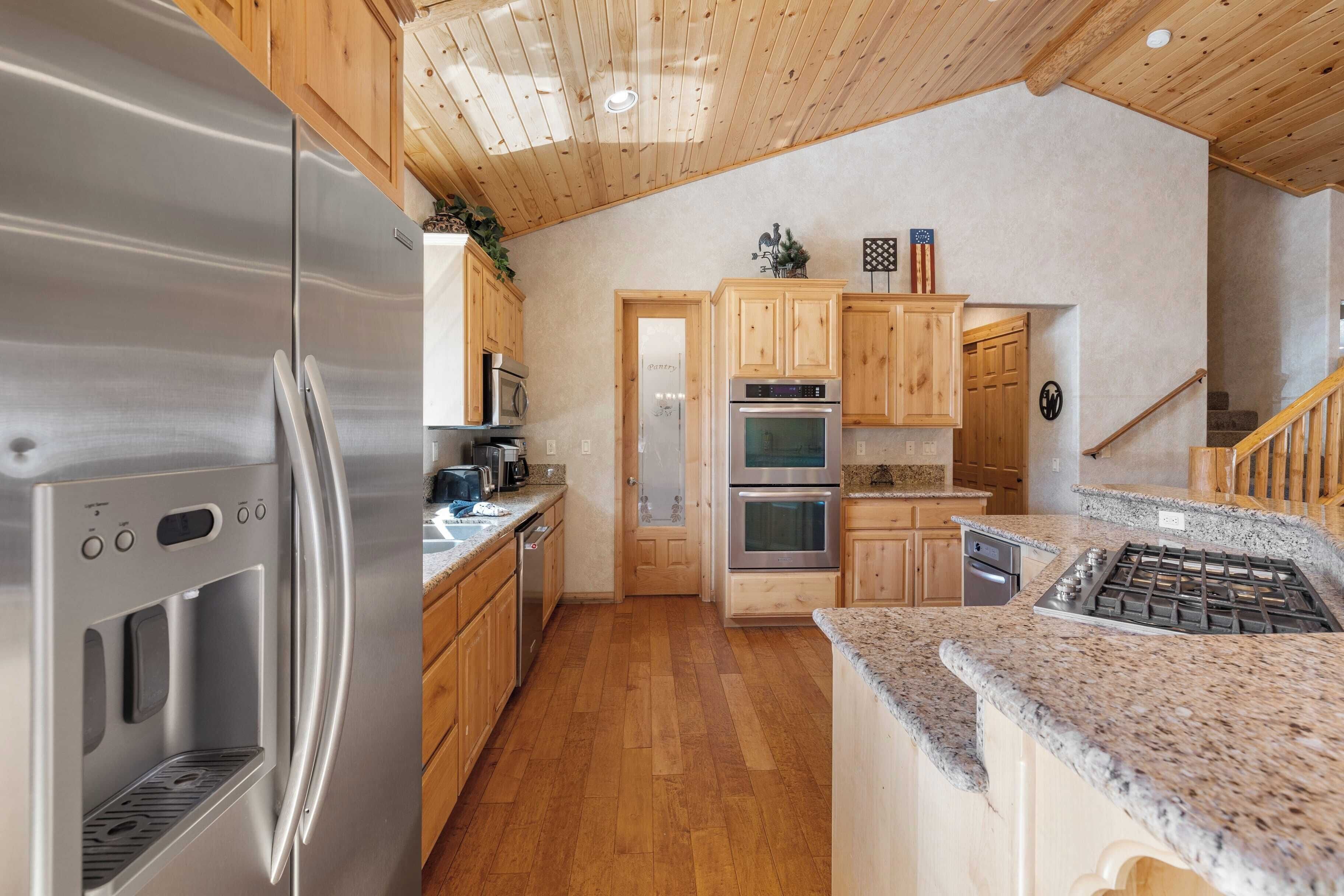 A modern kitchen with stainless steel appliances, wooden cabinets, and a granite countertop.