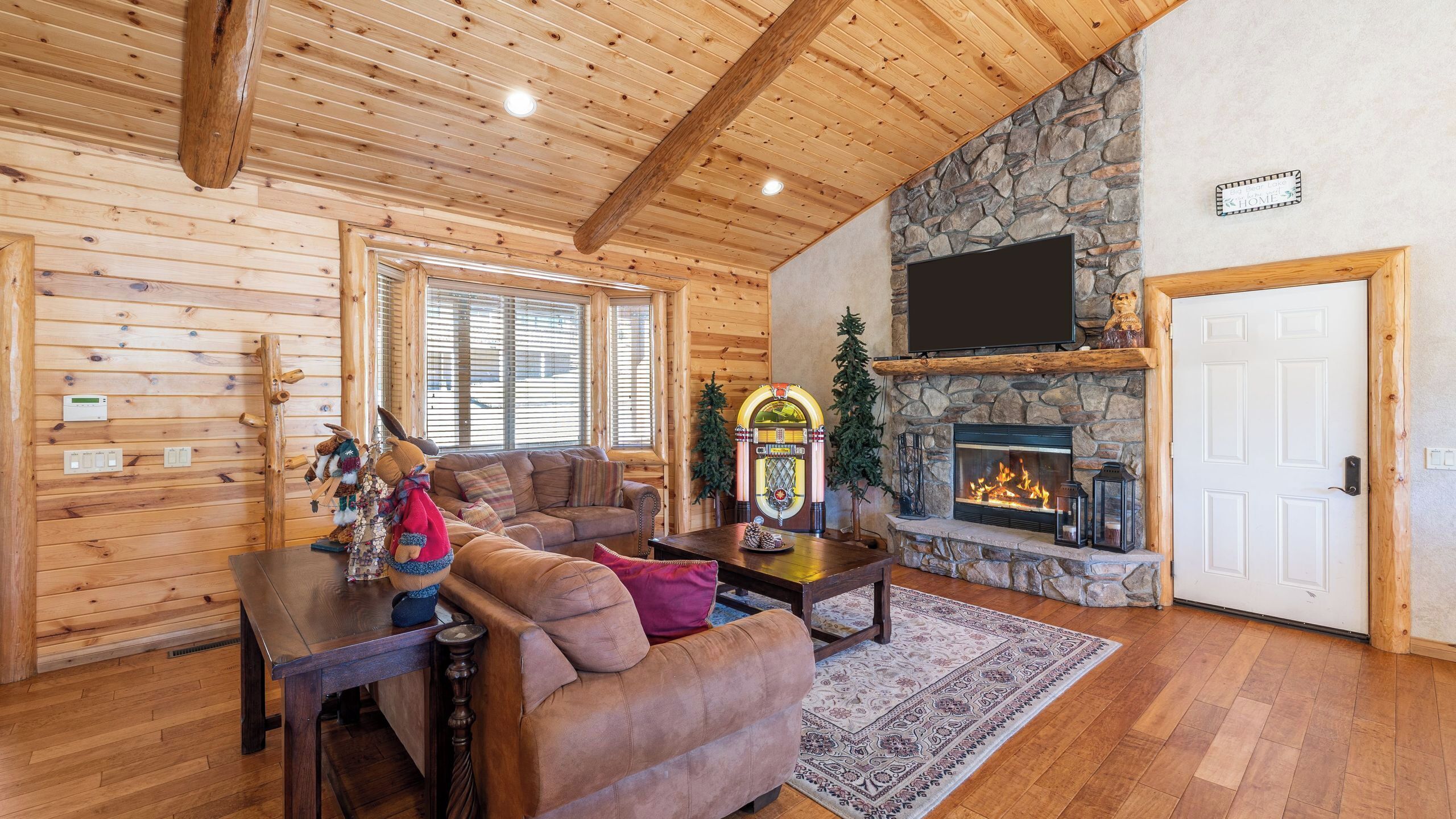 A log cabin interior with a fireplace, wooden walls, a sofa, and a television.