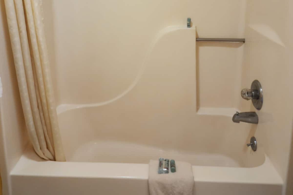 A bathroom with a bathtub, a towel rack, and a showerhead.