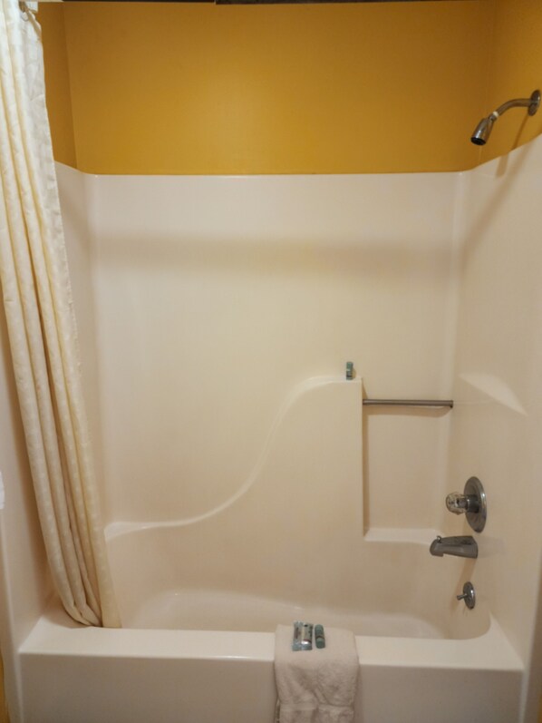 A bathroom with a bathtub, a towel rack, and a showerhead.