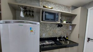 Eine kleine Küche mit einem weißen Kühlschrank, einer Mikrowelle und einem Spülbecken.