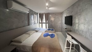 Ein modernes Hotelzimmer mit einem großen Bett, einem Schreibtisch und einem an der Wand befestigten Fernseher.