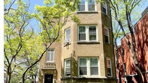 A two-story building with a brick facade, a front entrance, and a small front yard with grass. - Oak Park Queen (Oak Park)