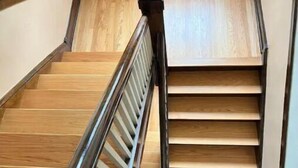 A wooden staircase with a handrail, leading to a landing with a light-colored wall and a window. - Oak Park Queen (Oak Park)