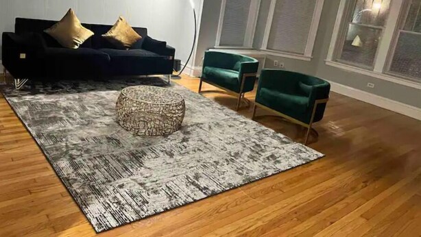 A living room with a dark blue sofa, a green armchair, and a patterned rug. - Oak Park Queen (Oak Park)