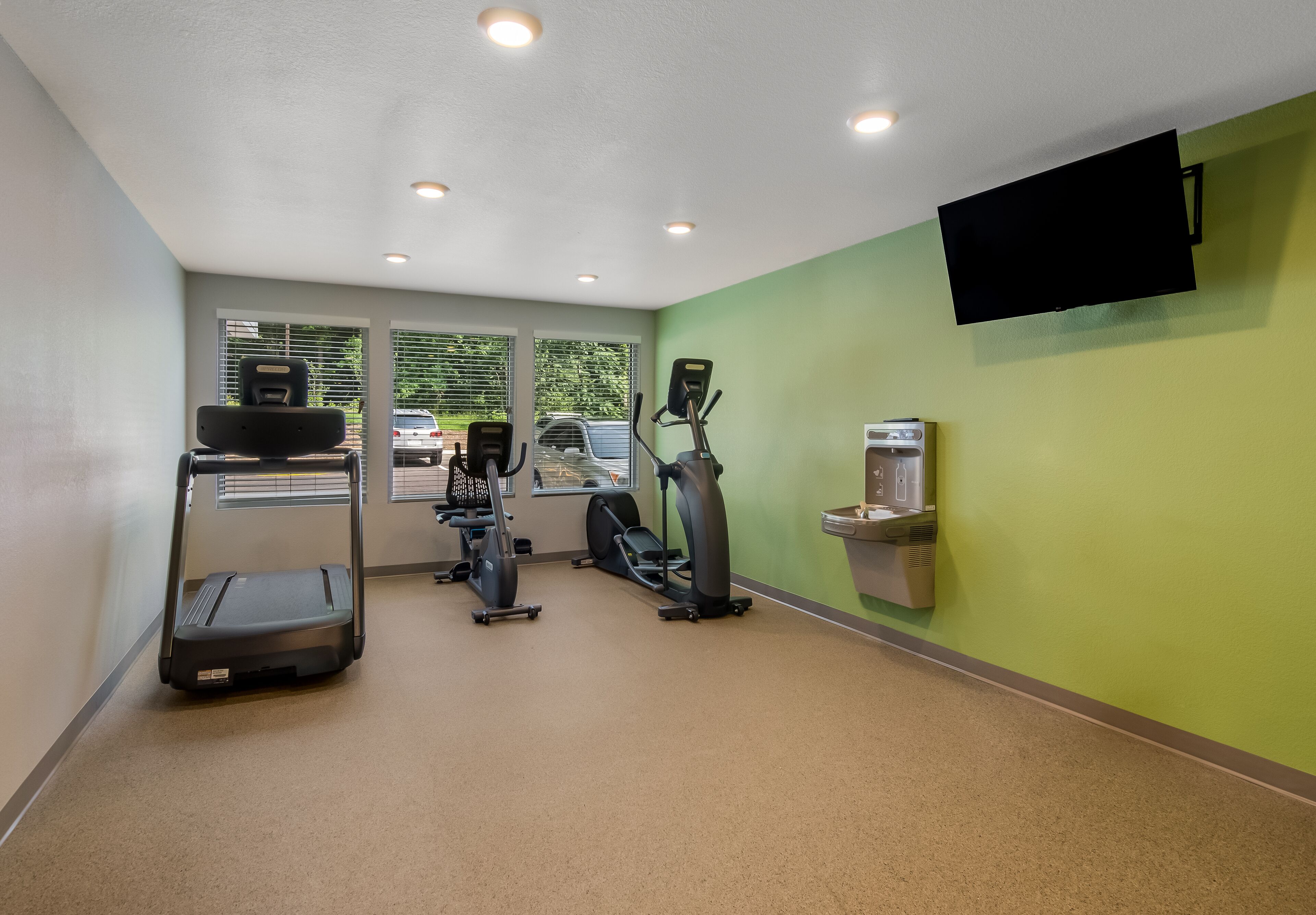 A gym with treadmills, elliptical machines, and a water dispenser.