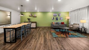 A modern room with a wooden dining table, chairs, a sofa, and a patterned rug.
