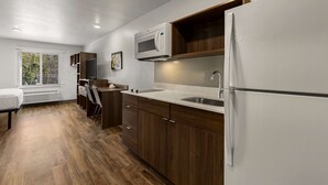 A modern kitchen with wooden cabinets, a built-in microwave, and a refrigerator.