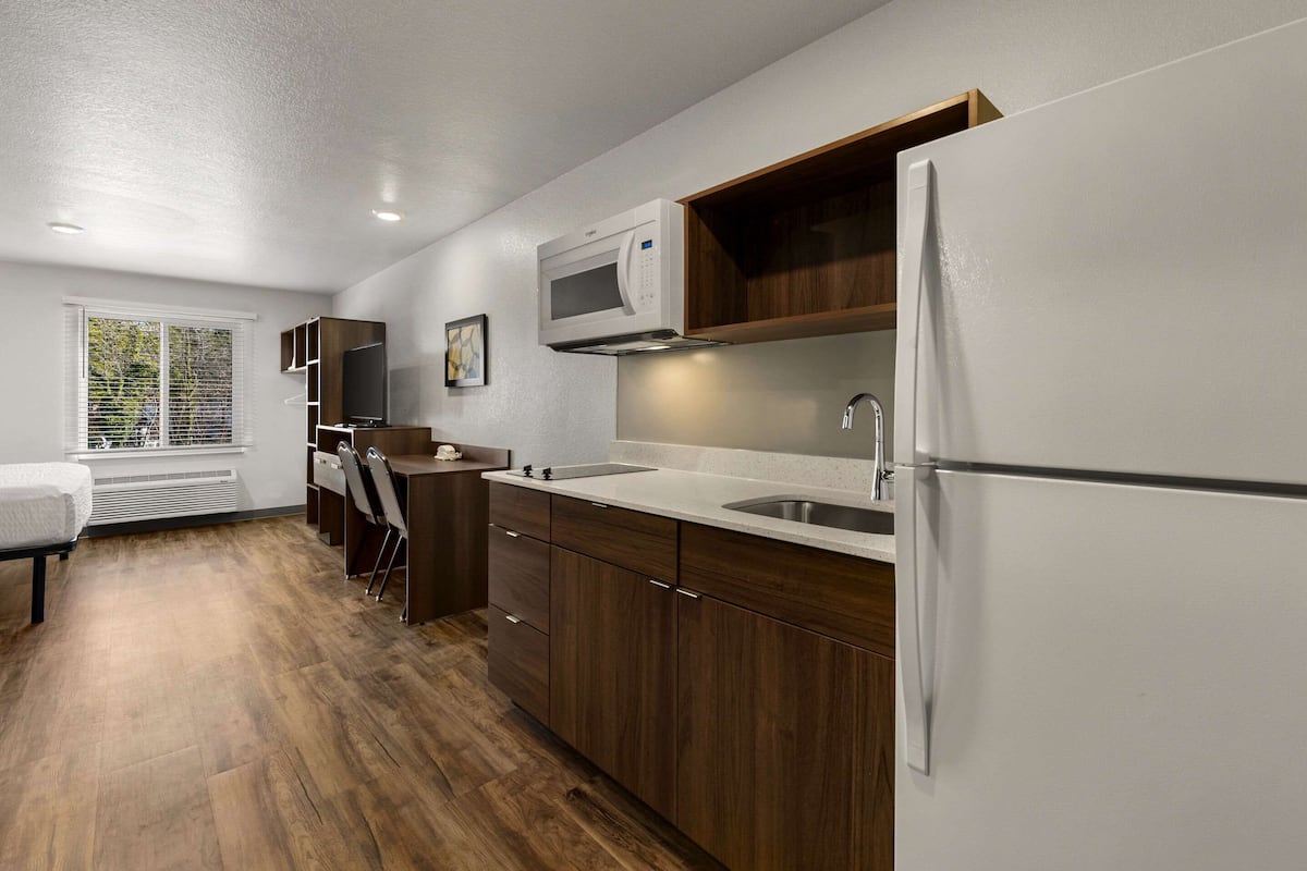 A modern kitchen with wooden cabinets, a built-in microwave, and a refrigerator.