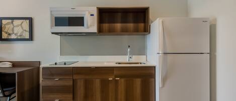 A compact kitchen with a microwave, sink, and refrigerator.