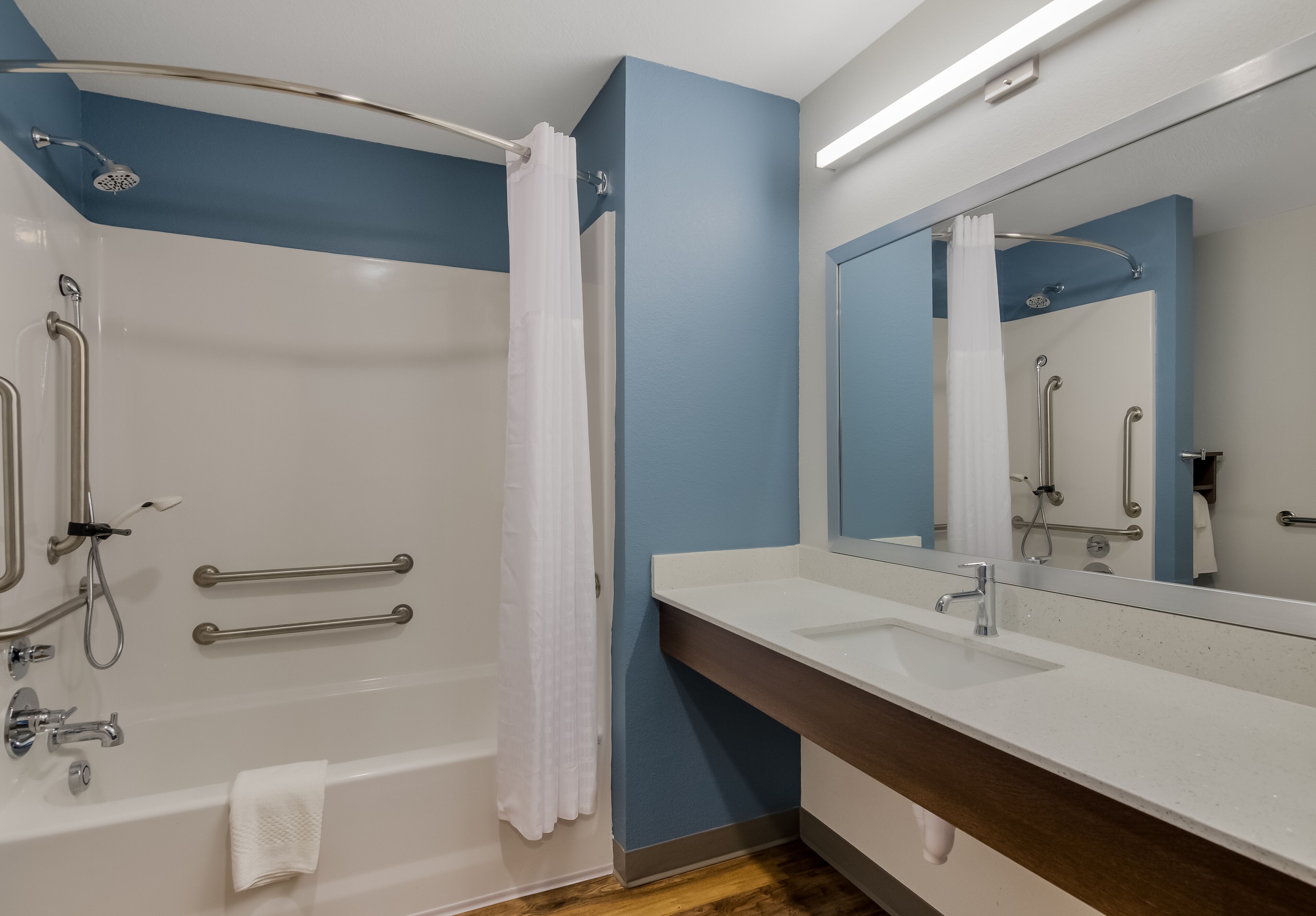 Un baño moderno con bañera, ducha y tocador con un espejo grande.