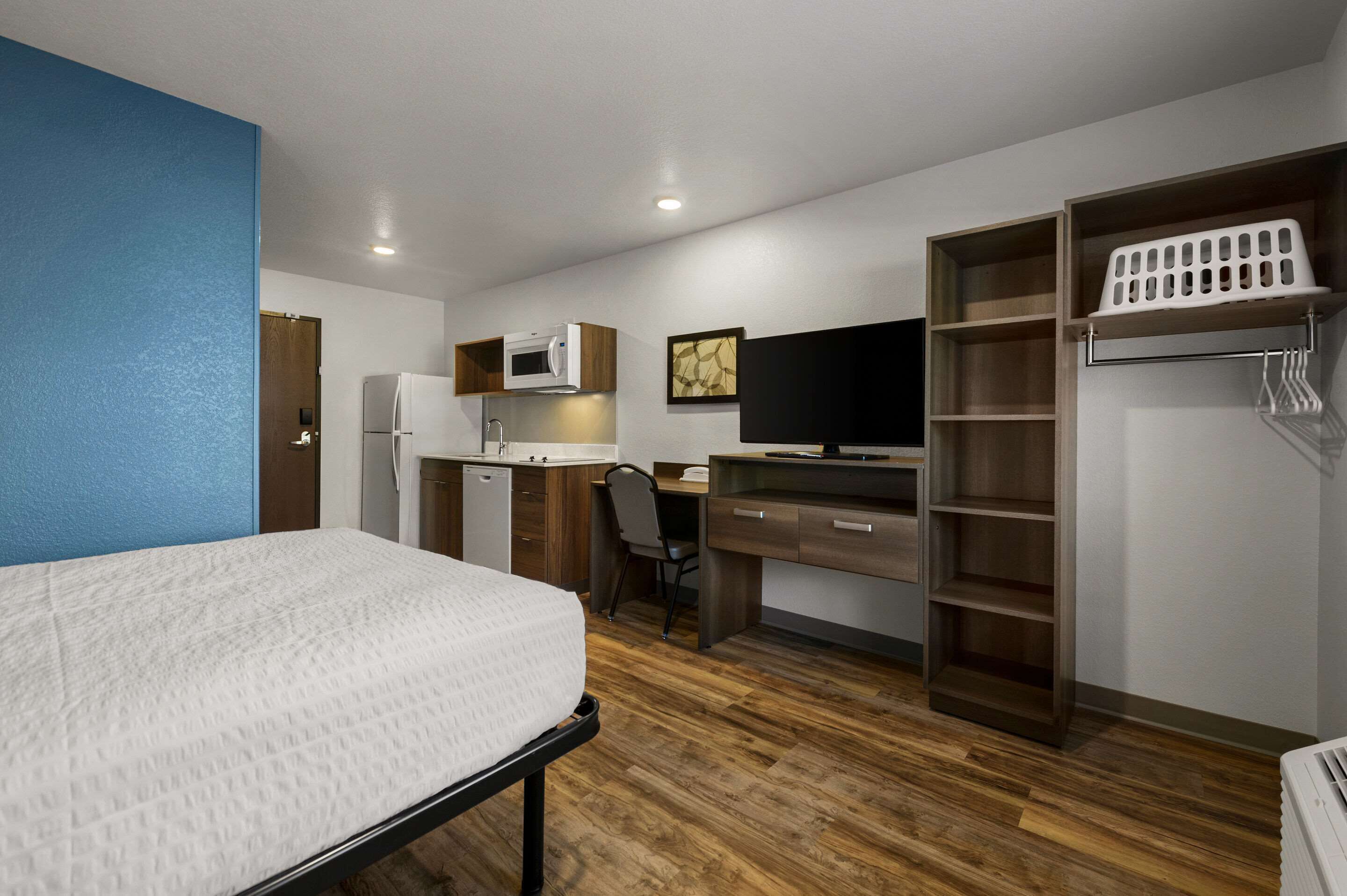 Ein kleines Hotelzimmer mit Bett, Küchenzeile, Schreibtisch und Kleiderschrank.
