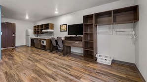 A modern kitchen with wooden cabinets, a built-in stove, and a dining area with chairs.