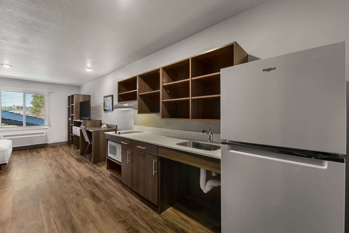 A modern kitchen with wooden cabinets, a built-in oven, and a stainless steel refrigerator.