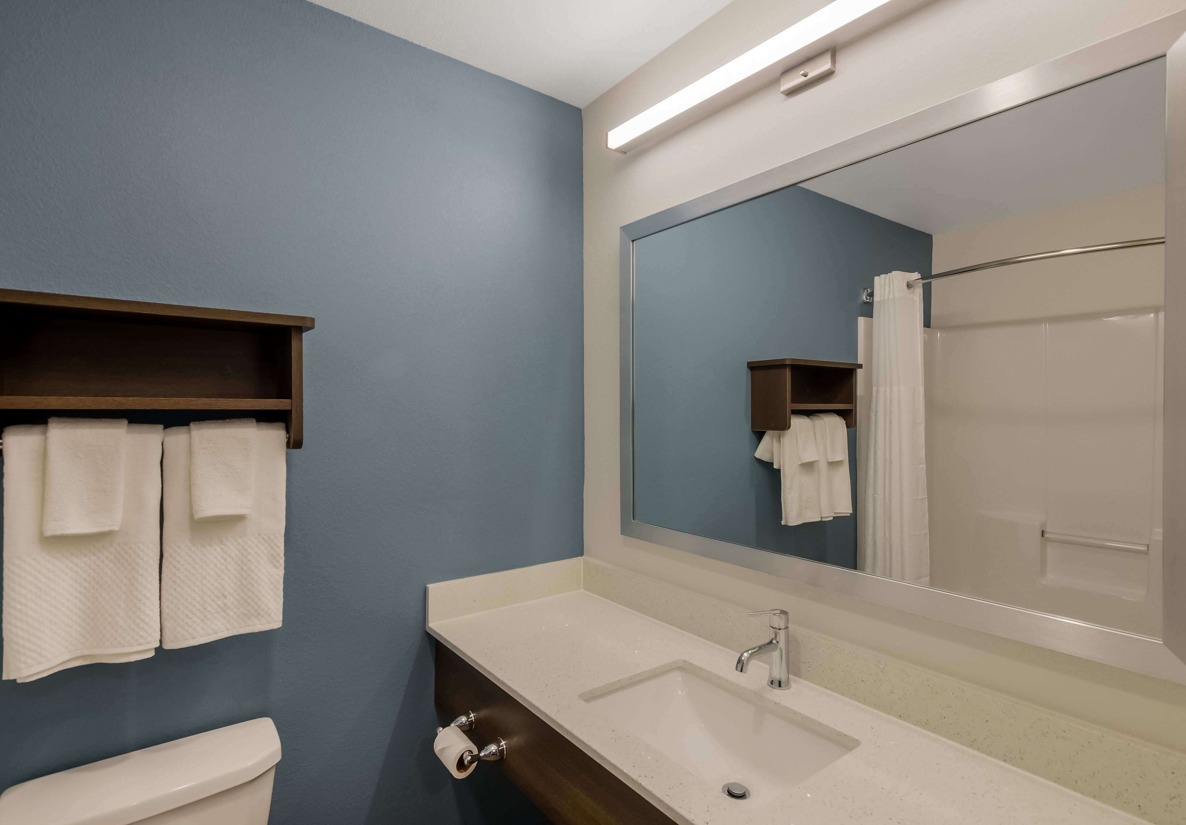 A bathroom with a white sink, a mirror, and a towel rack.