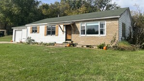 A single-story house with a garage, a front porch, and a number sign. - Ranch House at Edelweiss Winery & Events (Hermann)