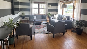 A modern living room with a sofa, armchairs, a coffee table, and a TV mounted on the wall. - Ranch House at Edelweiss Winery & Events (Hermann)