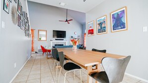 A dining area with a wooden table, black and grey chairs, a TV, and framed pictures on the wall. - Ideally Located, Stone Oak Extended Family Stay (San Antonio)