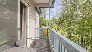 A balcony with a metal railing, a chair, and a table.