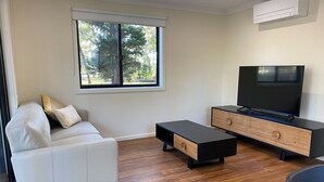 A modern living room with a sofa, a TV, a coffee table, and a wooden floor. - Wedderburn Caravan Park (Wedderburn)