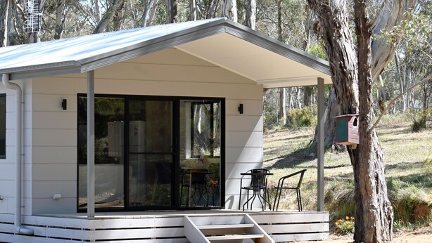 A small, single-story cabin with a covered porch and a sliding glass door. - Wedderburn Caravan Park (Wedderburn)