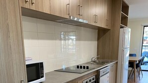 A modern kitchen with wooden cabinets, a stainless steel range, and a built-in microwave. - Wedderburn Caravan Park (Wedderburn)