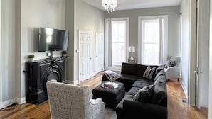 A living room with a fireplace, a television, a sofa, and a chair.