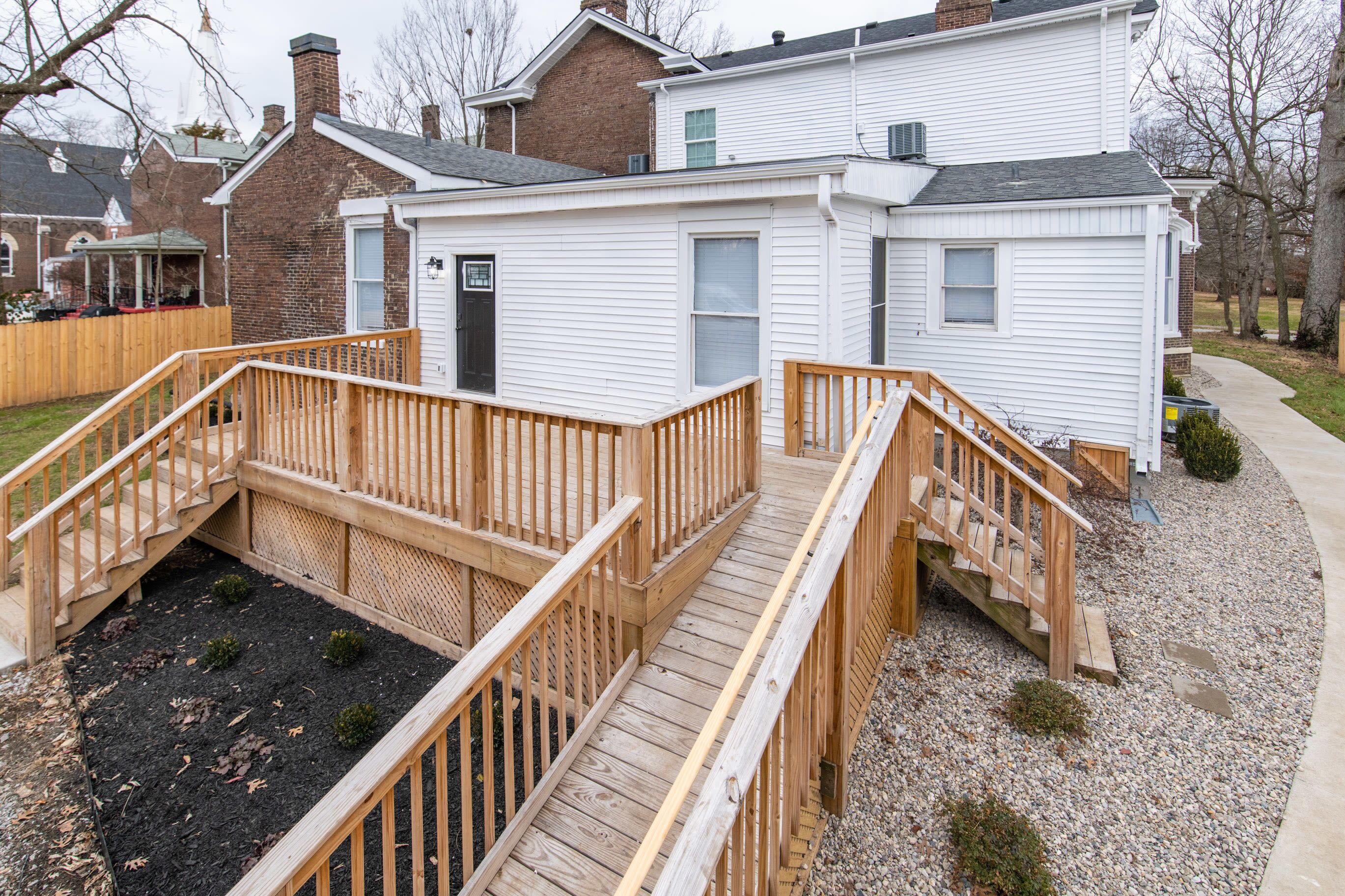 A two-story house with a wooden deck and a small garden area.