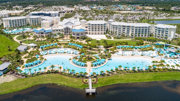 Ein Resort mit mehreren Schwimmbecken, einem Steg und einem großzügigen Gebäudekomplex.