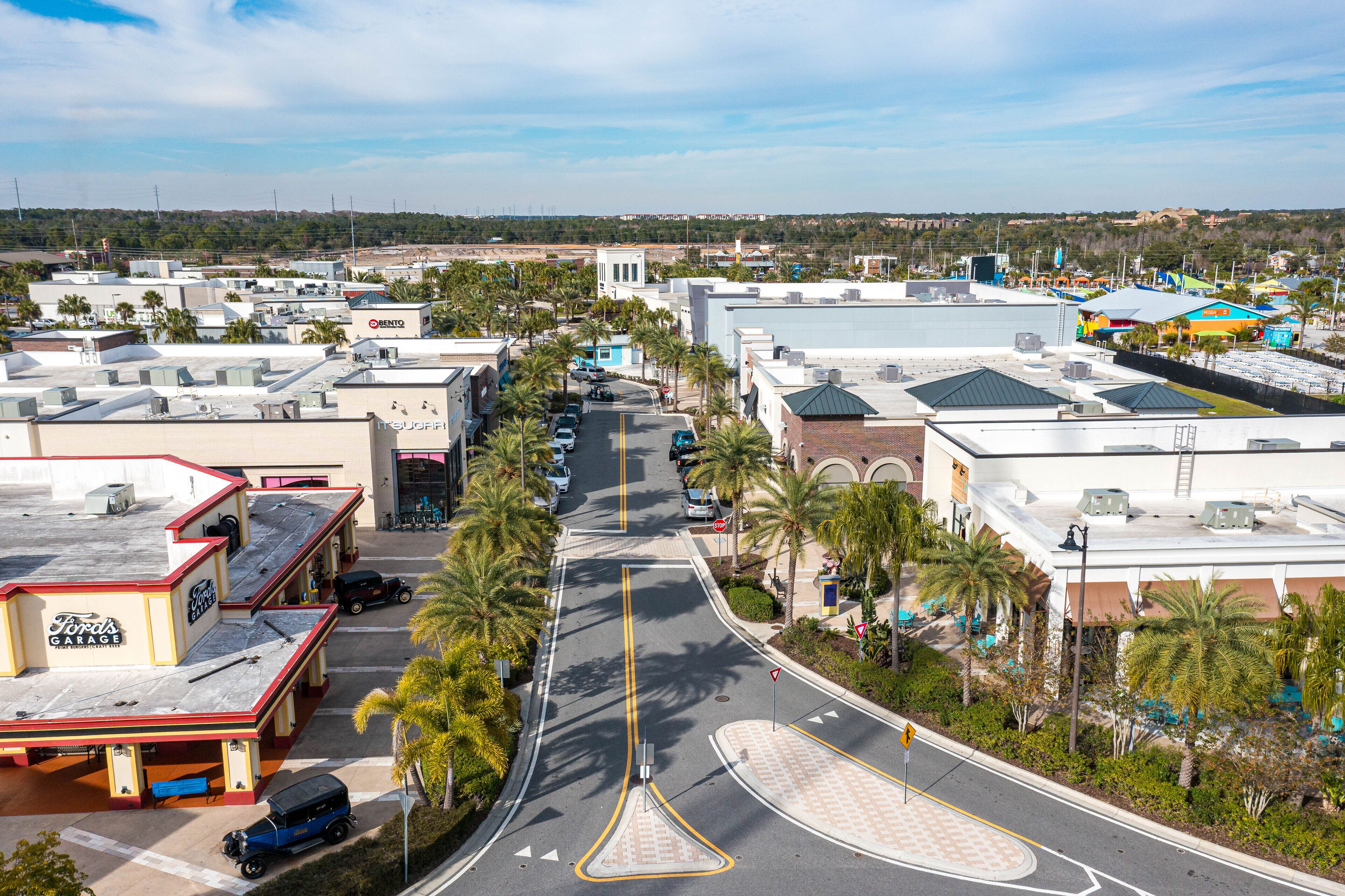 A commercial area with a parking lot, a gas station, and a building with a large sign.