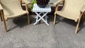 Two wicker chairs with a small white table and a potted plant between them.