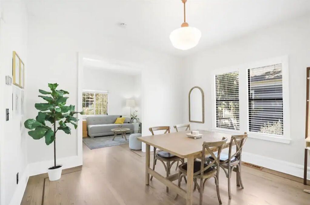 A dining area with a wooden table and chairs, a potted plant, and a hanging light fixture.